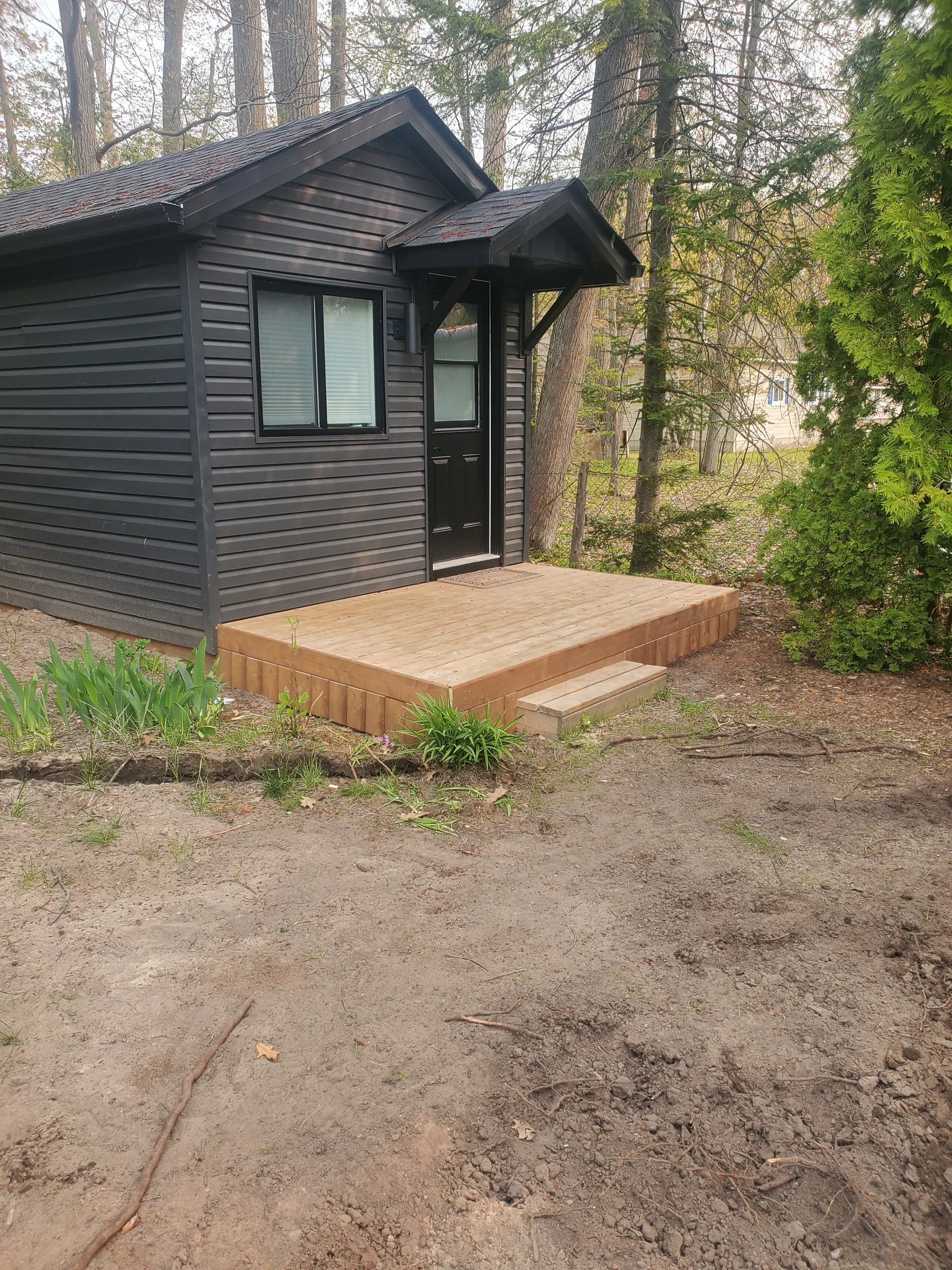 Finished Ferreira bunkie exterior with deck in a wooded setting