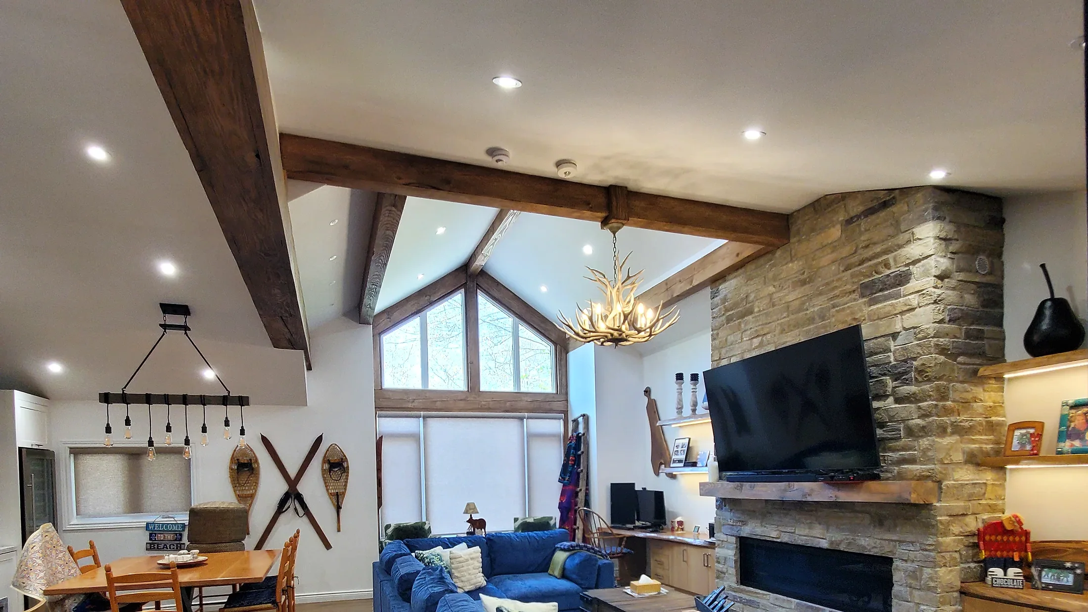 Finished Ferreira Contracting living space with exposed beams, stone fireplace, and open kitchen area